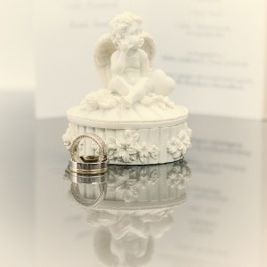 Üveglapon készült kreatív, tükröződő tárgyfotó, mely az ifjú pár személyes dolgait ábrázolja, angyalka és jegygyűrű